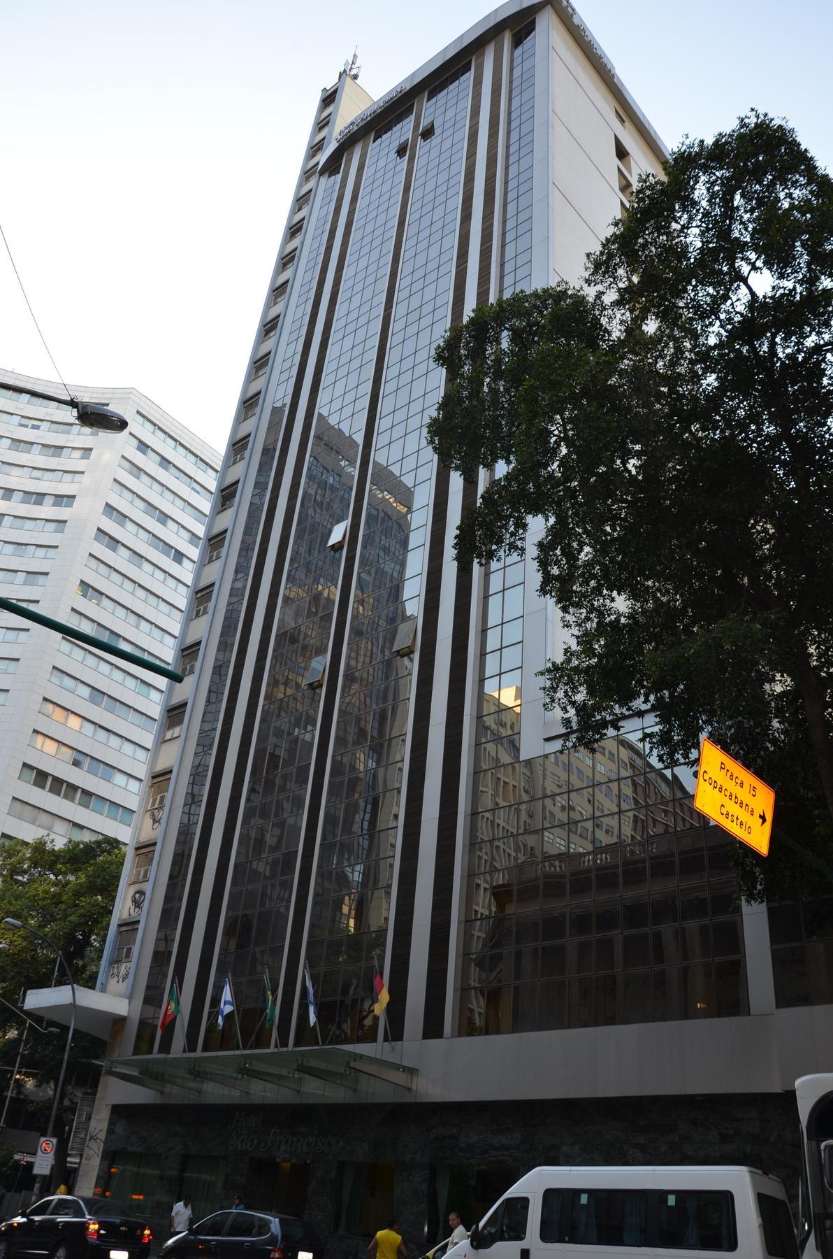ריו דה ז'ניירו Hotel Atlantico Tower מראה חיצוני תמונה The photo shows a city street with tall buildings. In the foreground, there is a modern glass skyscraper featuring reflective surfaces and vertical lines. Next to it, there's another building with a different architectural style, also made of glass. 
